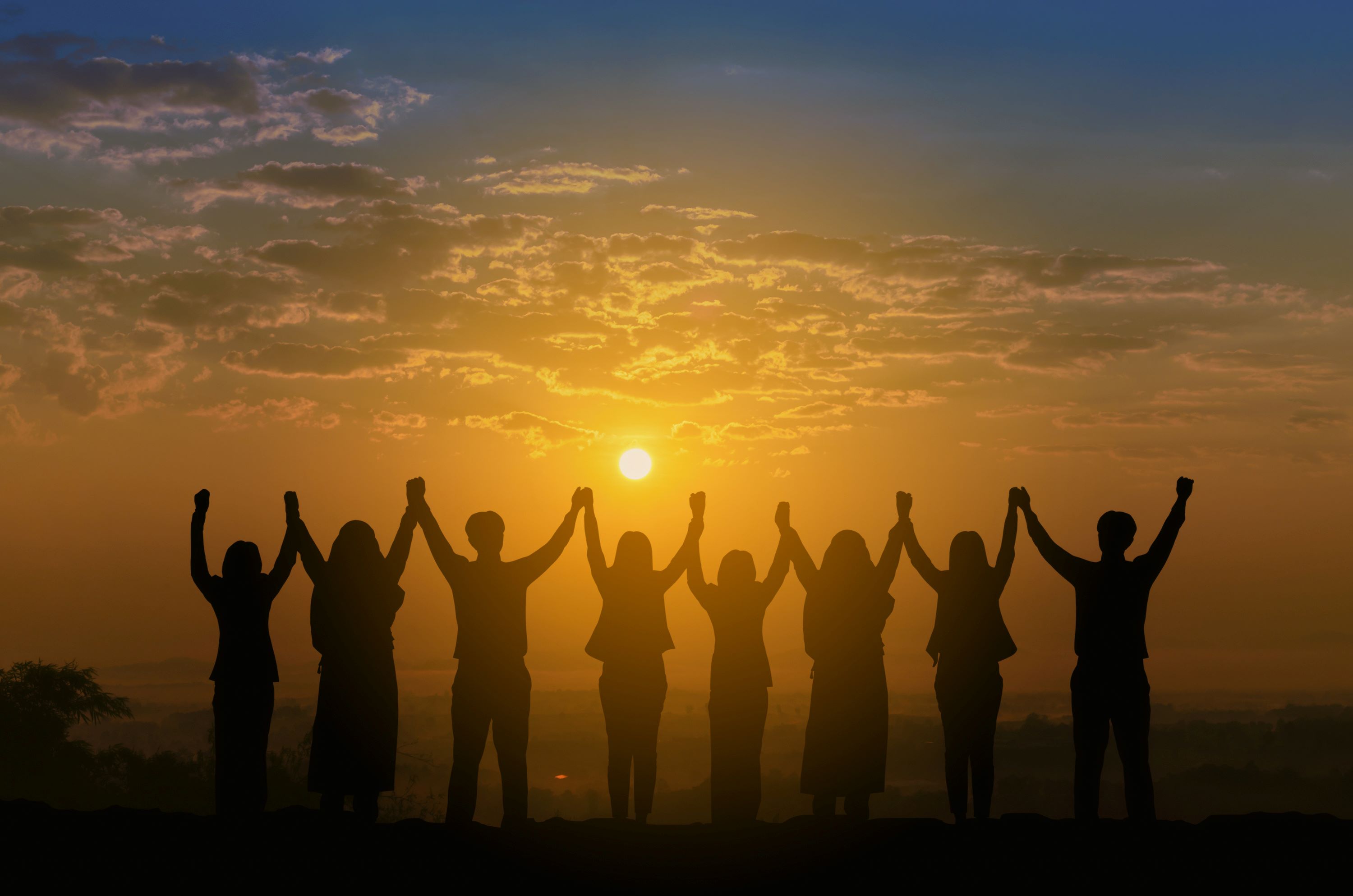Bild på människor som håller varandra i handen mot solen